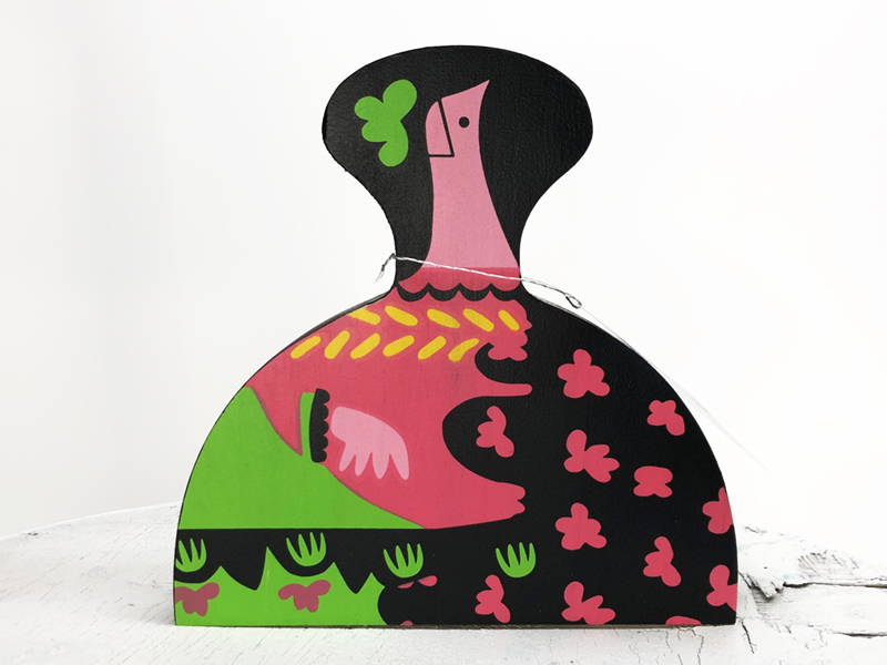 Menina Flor Verde de madera serigrafiada a 5 tintas, diseñada por Lucía Huertas, edición limitada de 100 unidades, 17x17x2 cm, presentada en bolsa kraft serigrafiada